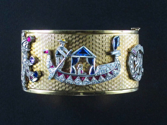 An Art Déco rare Yellow gold and platinum cuff bracelet with seven diamond and precious stone charms. USA, 1940 c.a.
