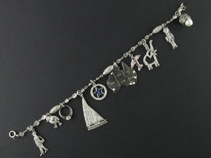 An Art Déco platinum diamond and precious stone bracelet with 10 charms.