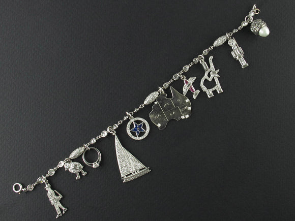 An Art Déco platinum diamond and precious stone bracelet with 10 charms.