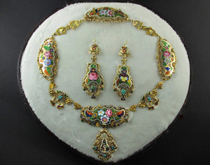 A yellow gold en repoussé enameled parure. Composed of a necklace and a pair of earrings of flowers design. In original fitted box. Napoli XIX Century