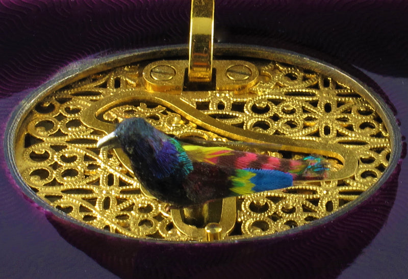 A silver-gilt singing bird automation box with guilloche in translucent violet and green enamel , the oval cover enamelled opening to reveal a singing feathered bird. Swiss 1960