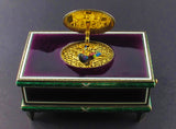A silver-gilt singing bird automation box with guilloche in translucent violet and green enamel , the oval cover enamelled opening to reveal a singing feathered bird. Swiss 1960